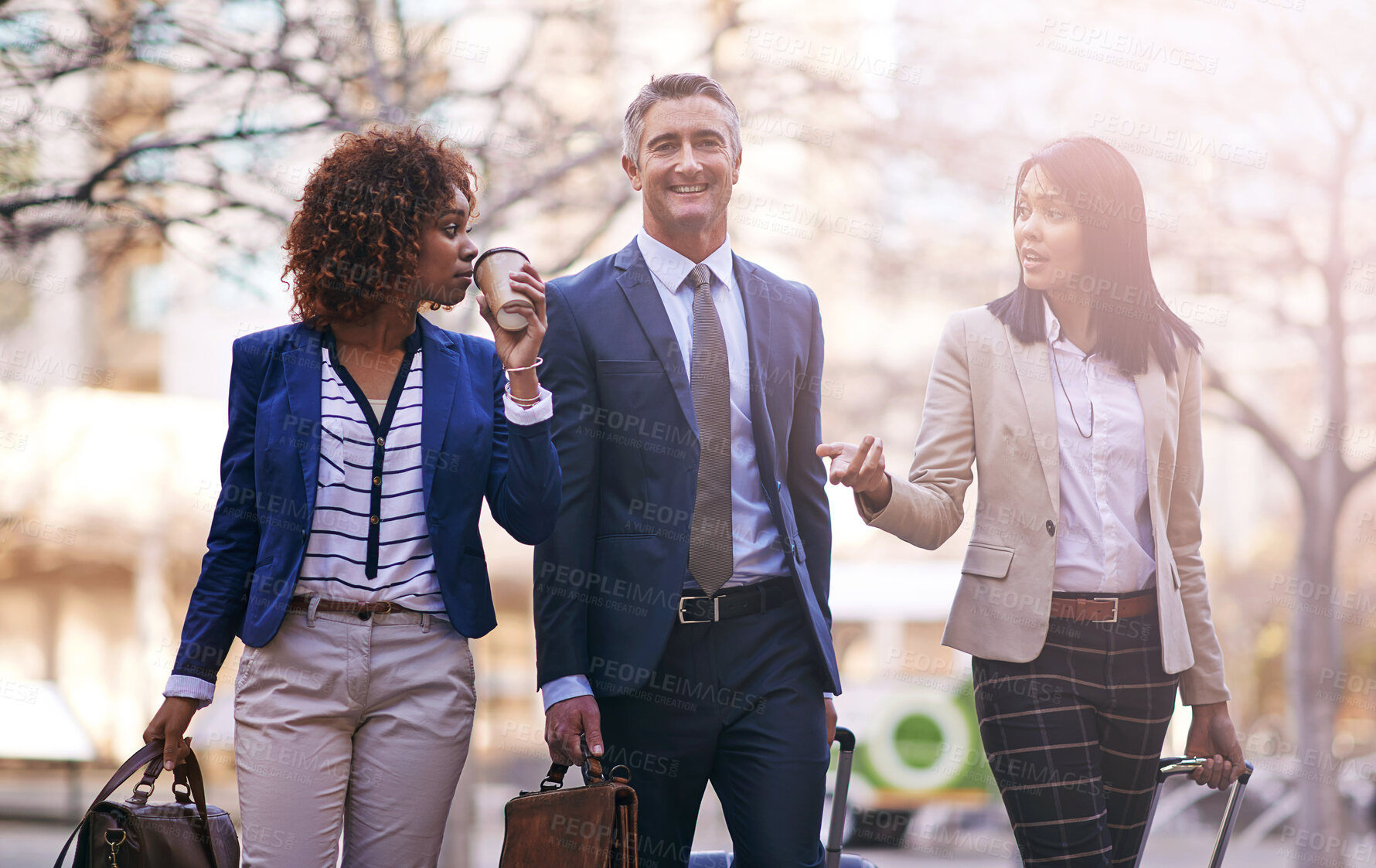 Buy stock photo Happy, business people and corporate travel for work trip, remote conference and walking in city. Smile, formal team and commute to seminar for diversity, journey and collaboration with lens flare