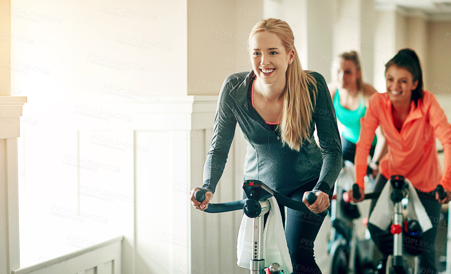 Buy stock photo Cycling class, fitness instructor and women riding exercise bikes together for cardio workout in gym. Excited, female people and health for training with coach for motivation, support and advice