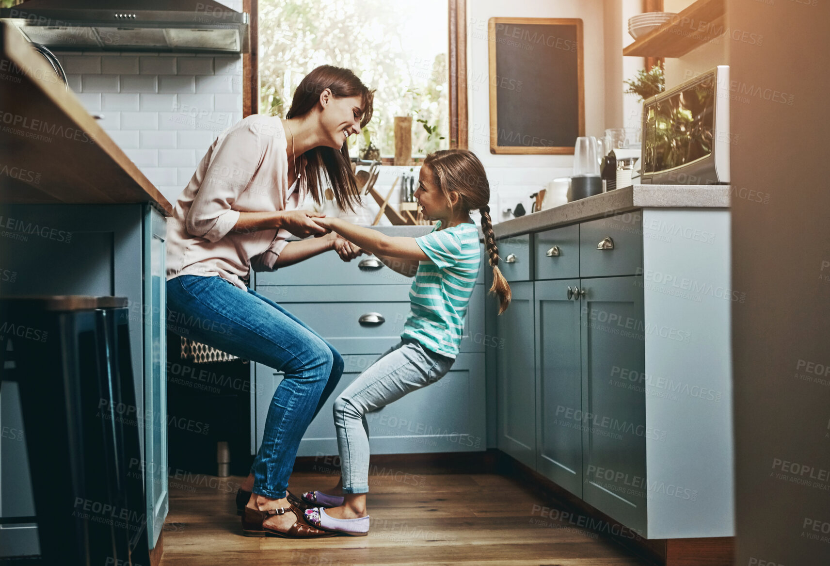 Buy stock photo Playful, daughter and mom with fun in kitchen for weekend bonding, humor and support in childhood. Happy, smile and woman with little girl at family home for care, funny joke and love in motherhood