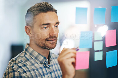 Buy stock photo Sticky notes, man and writing in office for planning, tasks and schedule glass board. Businessperson, strategy and idea on paper for calendar, brainstorming and agenda on window in workplace