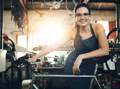 Buy stock photo Woman, bicycle shop and portrait for maintenance work, startup with transport service. Bike, mechanic and female entrepreneur in workshop with glasses, happiness for sustainable business with apron