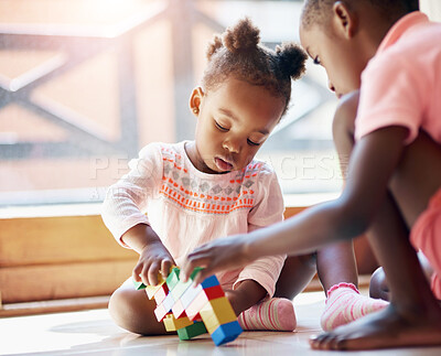 Buy stock photo Black child, little girl and siblings playing with blocks or toys together on floor in living room at home. Young African, baby or toddler with playful sister for bonding, help or building at house