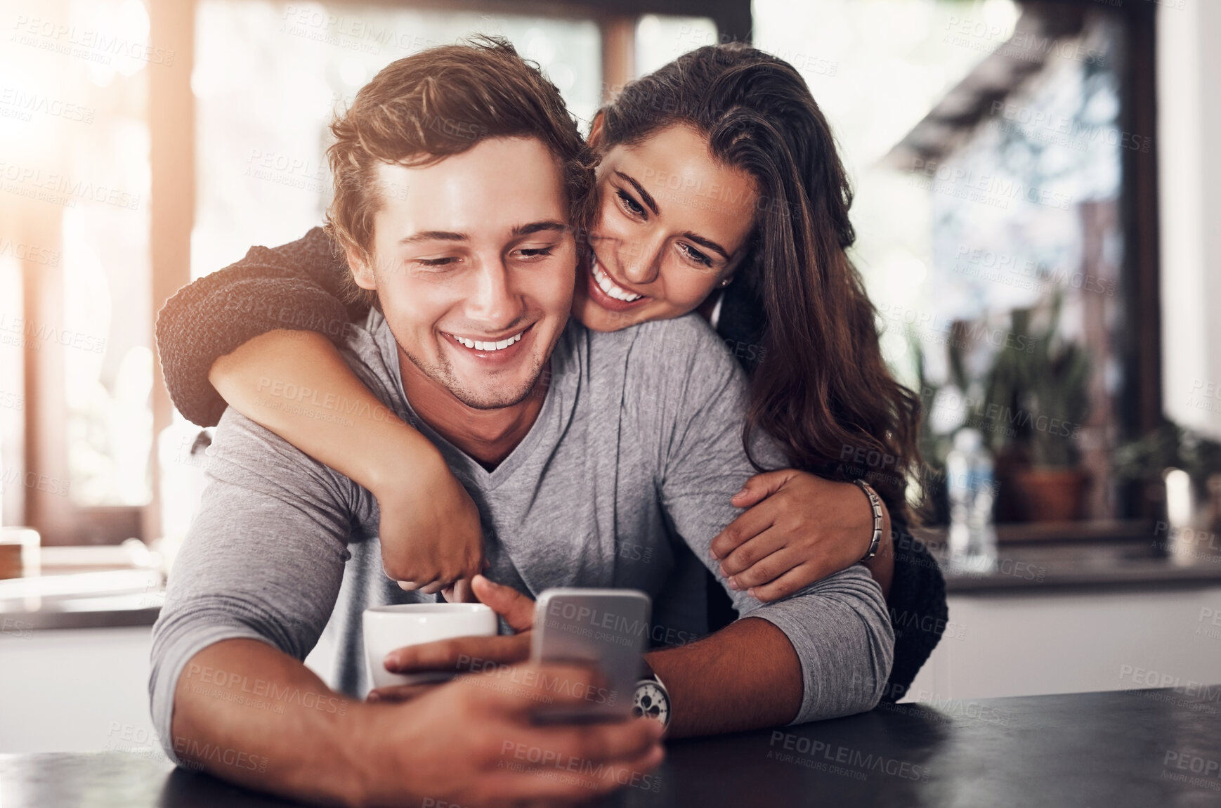 Buy stock photo Happy, couple and hug with phone in kitchen for communication, website or scroll on social media. Man, woman and love with tech in morning for post, notification or online relationship update at home