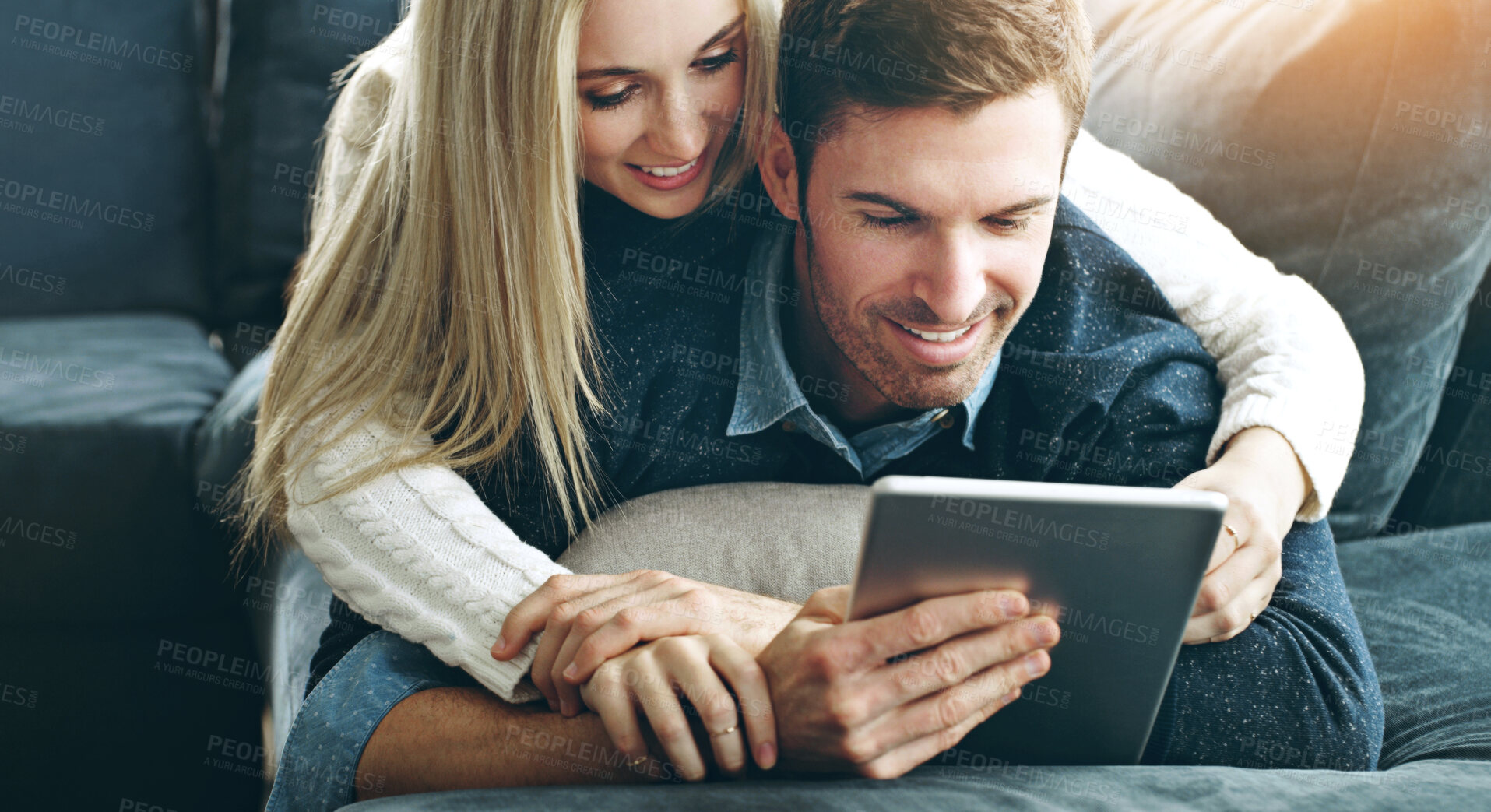 Buy stock photo Couple, tablet and hug or online in home with search for holiday, discount offers on travel or web streaming. People, smile and embrace in living room with bonding, social media browsing and support
