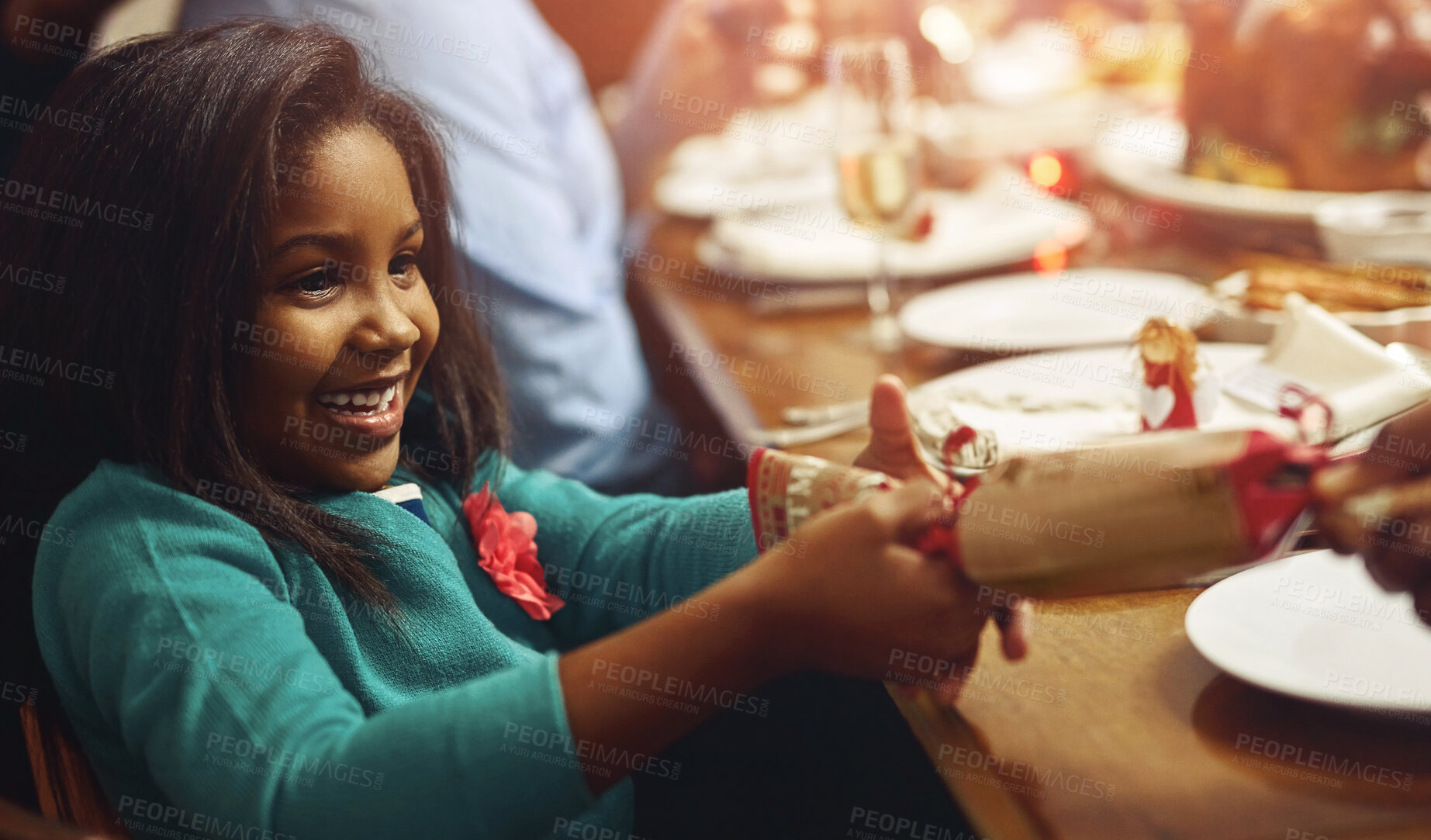 Buy stock photo Celebration, Christmas cracker and girl child at table in dining room of home for festive excitement. December, holiday or smile and cute kid in apartment with family together for social gathering