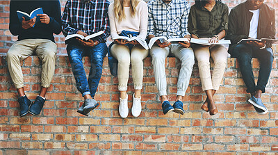 Buy stock photo Students, group and books on wall with legs, learning and reading for development at college. People, friends and scholarship for education, information and knowledge for future at university campus