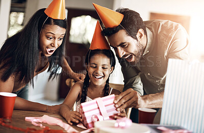 Buy stock photo Birthday, parents and child gift with surprise, present and excited from happy event and celebration. Family, home and young girl with box, package and fun hat with love, gratitude and smile at table