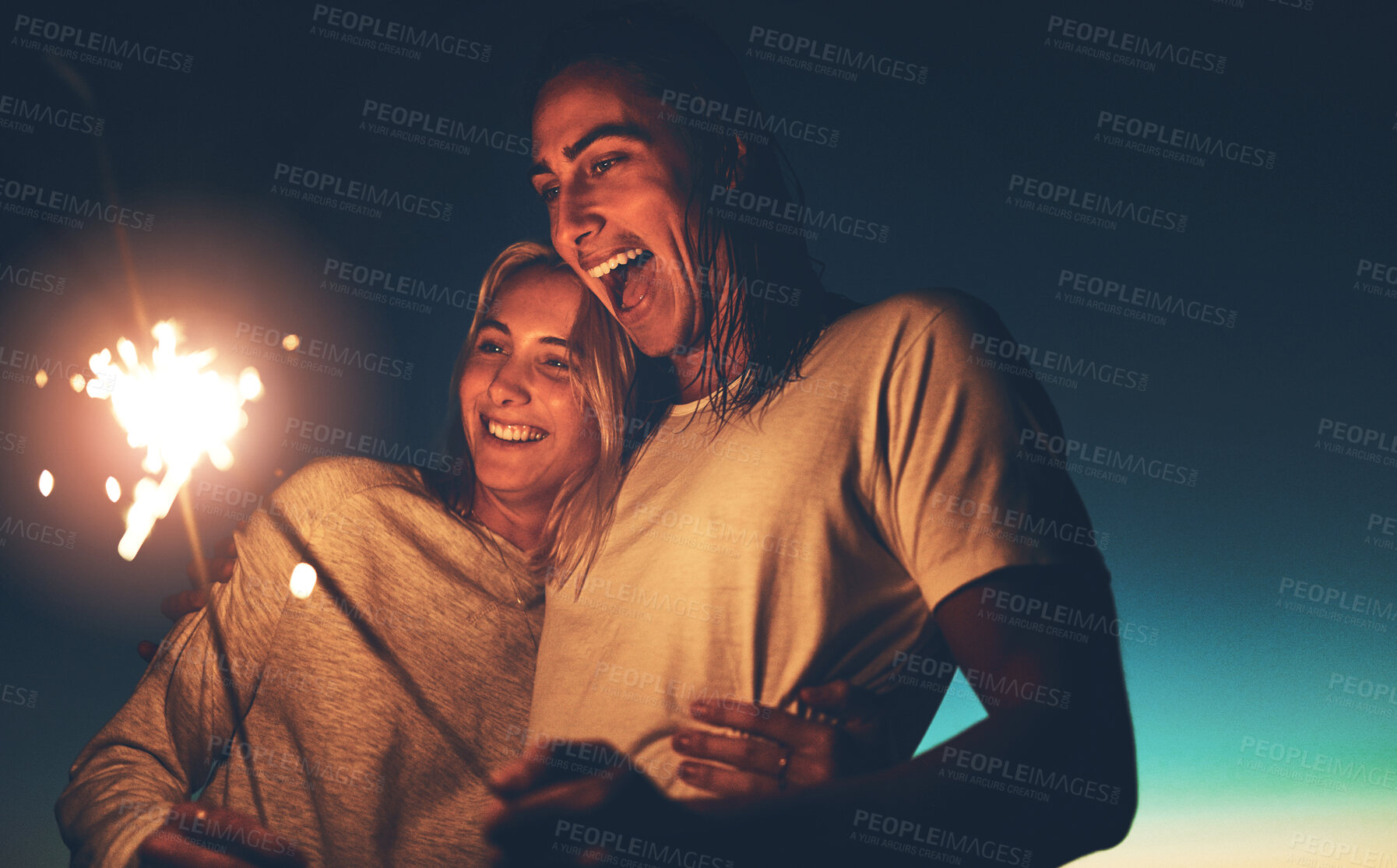 Buy stock photo Night, sparkler and couple with hug for love, romance and healthy relationship with trust and happiness. Firecracker, happy man and woman with smile for celebrate anniversary together in dark outdoor