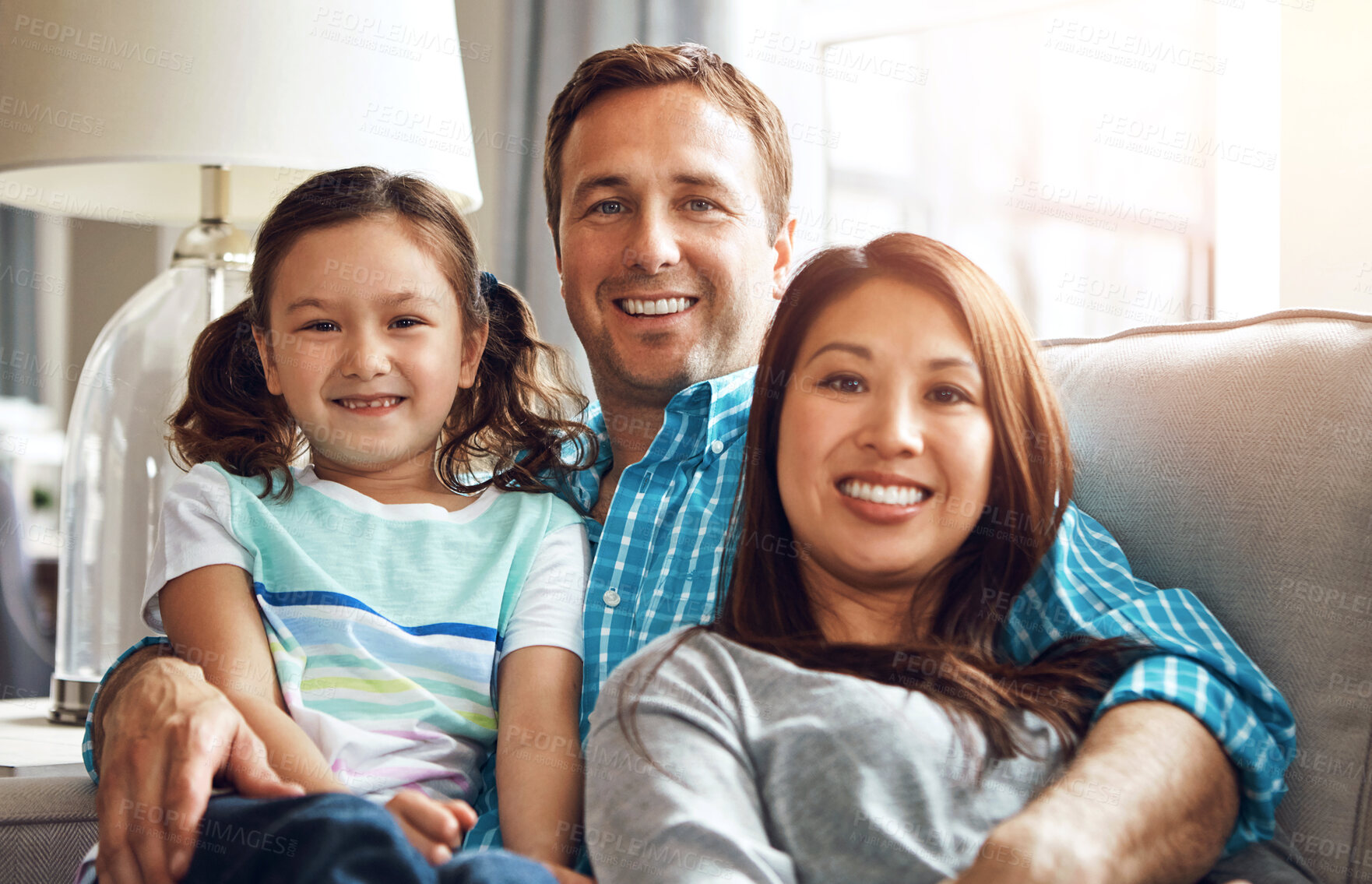 Buy stock photo Interracial parents, girl and portrait on sofa with smile, hug and relax with care, diversity and happy in family home. Father, mother and daughter with embrace, connection and love on lounge couch