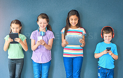 Buy stock photo Studio, technology and group of children for elearning, education and online research with smile. Happy students, girls and boy with digital app of tablet, smartphone and headphone by blue background