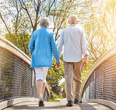 Buy stock photo Back, bridge and senior couple holding hands, walking in park together for bonding or retirement. Garden, love or nature with elderly man and woman outdoor in summer for relationship or wellness