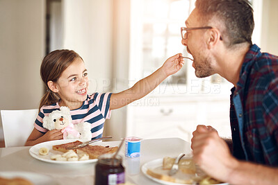 Buy stock photo Breakfast, feeding and daughter with dad, smile or morning in kitchen, toast or dining table in home. Healthy, family or food for father, child and man in house, eating and bonding with love together