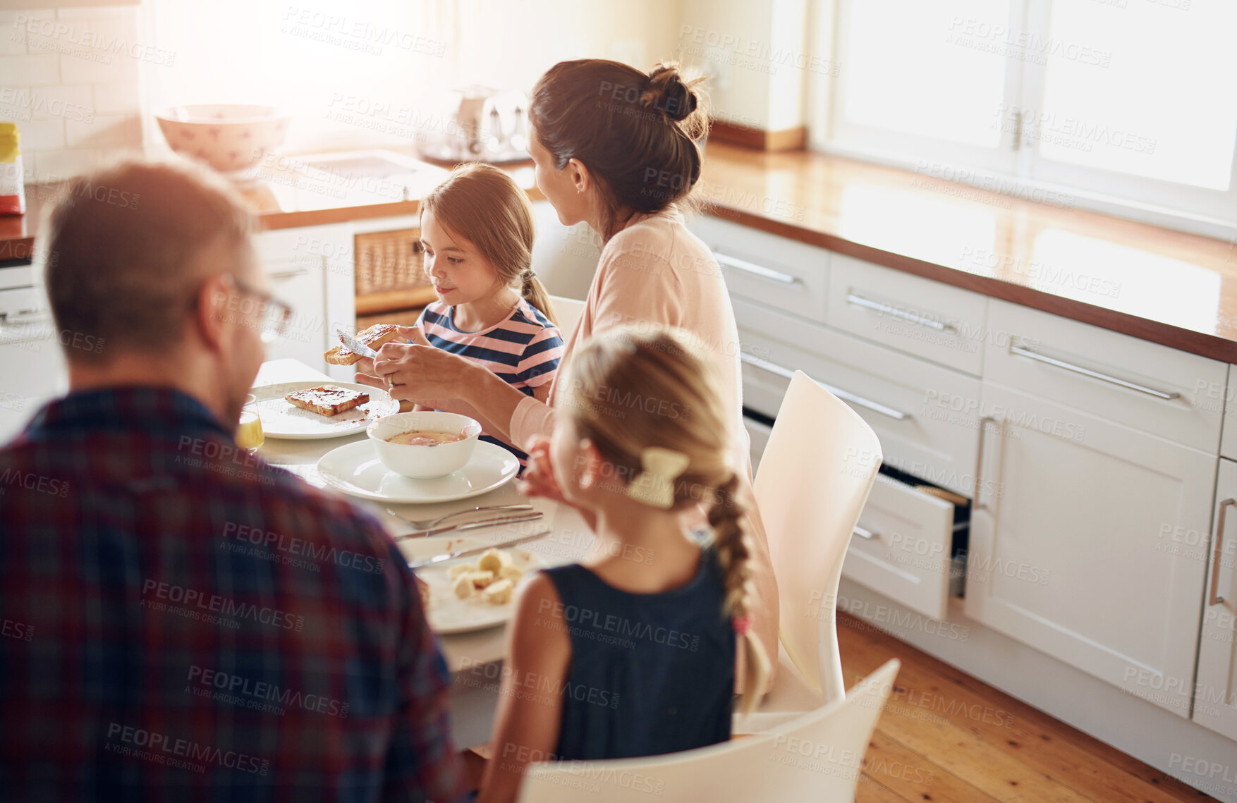 Buy stock photo Family, food and parents with children at table for breakfast, eating and bonding together in kitchen. Morning, happy woman and man with young kids for healthy meal, nutrition and hunger in home