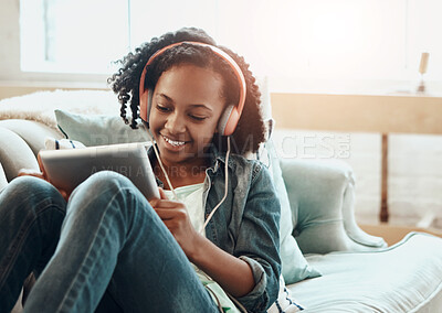 Buy stock photo Happy girl, headphones and listening with tablet on sofa for online streaming, music or entertainment at home. Young female person, child or student in relax with smile on technology for audio