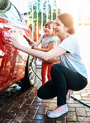 Buy stock photo Love, mother and daughter washing car outdoor for fun, learning or teaching responsibility and bonding. Water splash, hose or woman with kid in driveway for soap foam, cleaning or vehicle maintenance