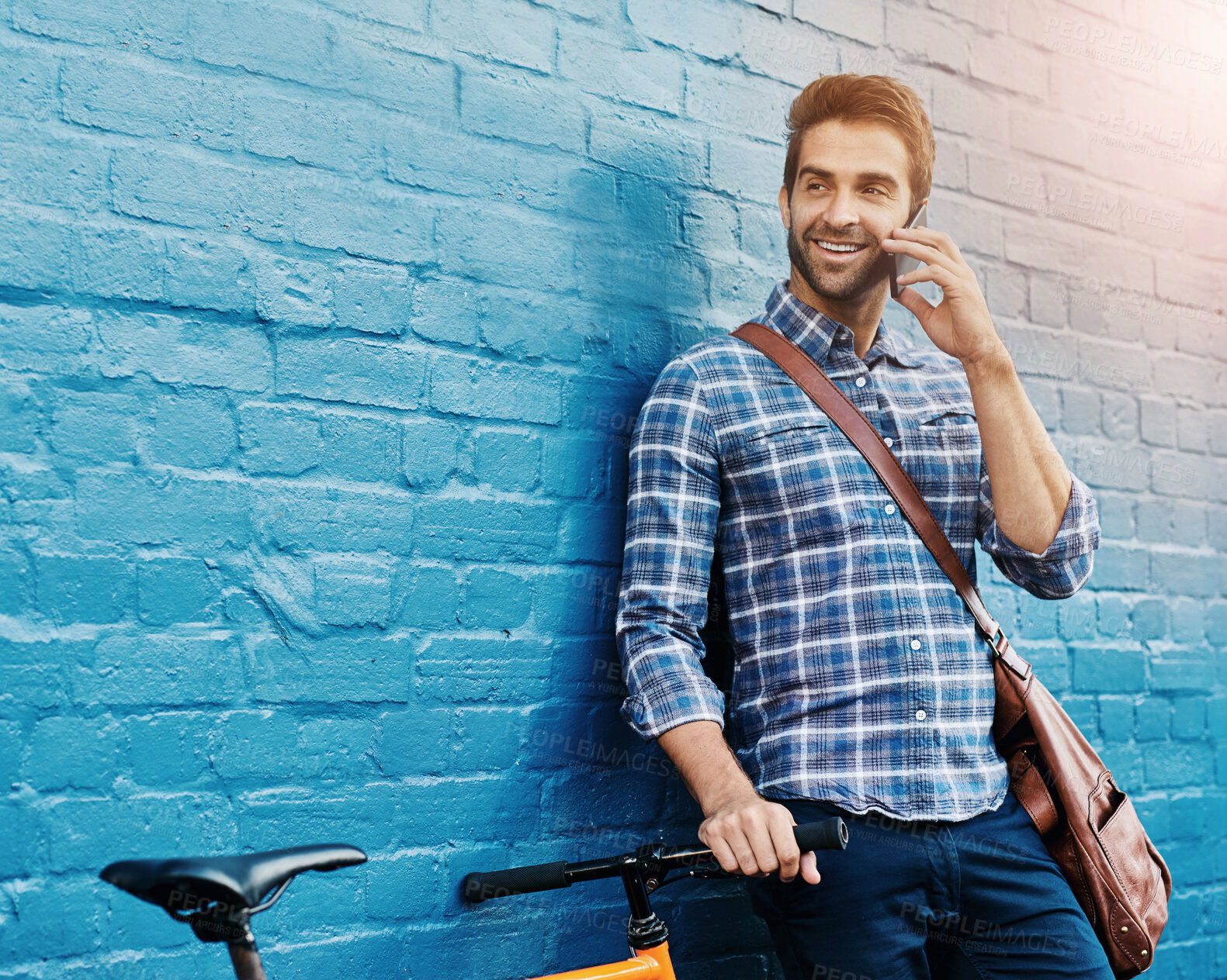 Buy stock photo Conversation, phone call and happy man on bike in city for eco friendly transportation. Mobile, talking or person with bicycle for communication, commute or travel plan by space outdoor on brick wall