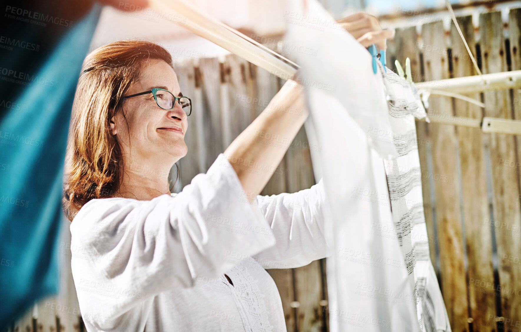 Buy stock photo Smile, woman and laundry with hanging in backyard for cleaning, hygiene and sanitation in sunshine. Wet, washing and female person with housework for fresh fabric, care and maintenance on weekend