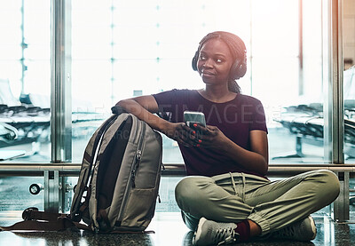 Buy stock photo Travel, headphones and black woman with phone at airport for music, streaming or immigration. International, journey and person with tech on floor for network, connection or online flight information