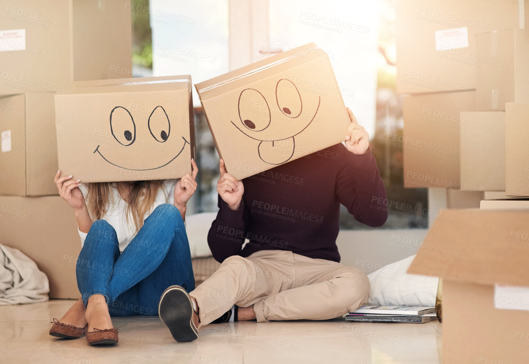 Buy stock photo New home, box and couple with emoji face on floor for property, moving day and mortgage. Homeowner, real estate and man and woman with funny drawing for relocation, packing and rental apartment