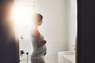 Buy stock photo Pregnant, woman and holding belly by mirror for progress, growth and love in bathroom. Maternity, girl and prenatal care at home for motherhood, support or thinking of future in parenthood with touch