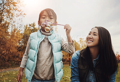 Buy stock photo Mom, girl and blowing bubbles in park with smile for fun, playing and bonding with child development. Asian parent, woman and happy with kid in garden on break for care, support and trust as family