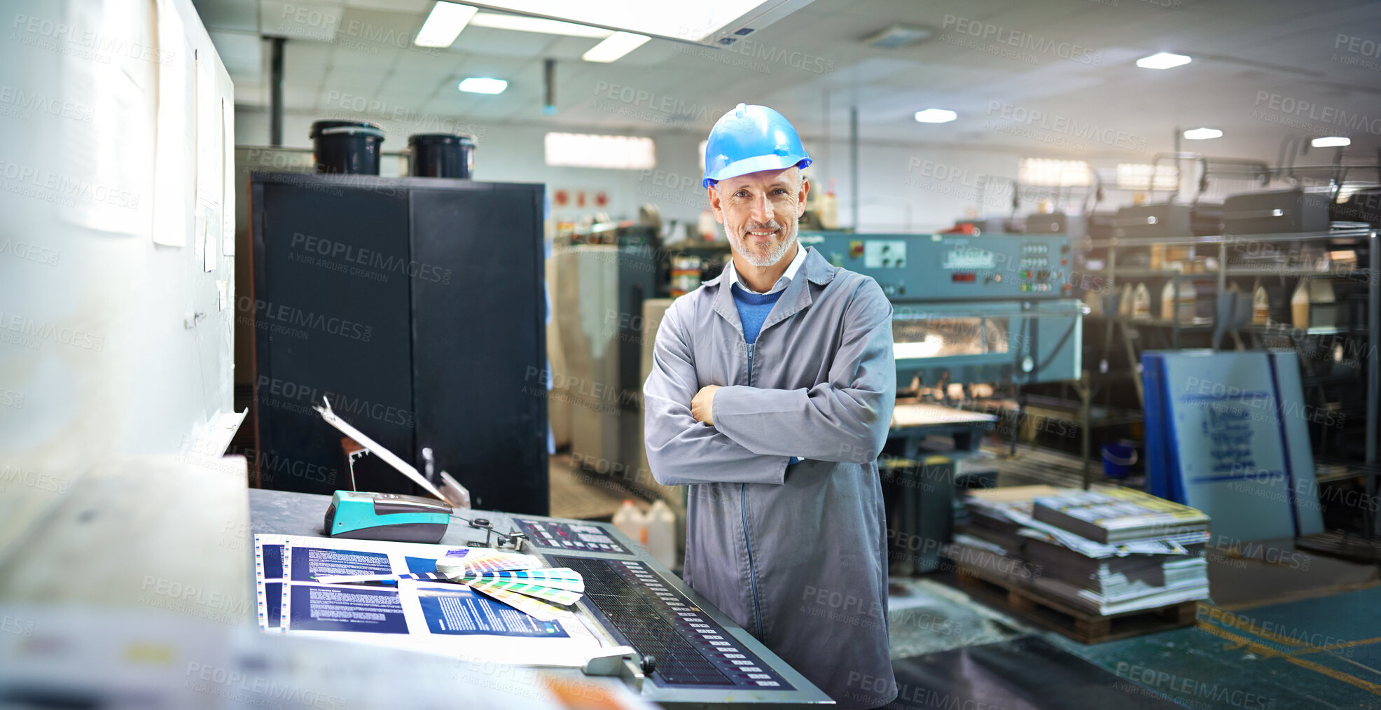 Buy stock photo Man, portrait and arms crossed in factory for printing by machine, maintenance and production at job. Mature person, smile and helmet in industrial warehouse for design, brochure or press for paper