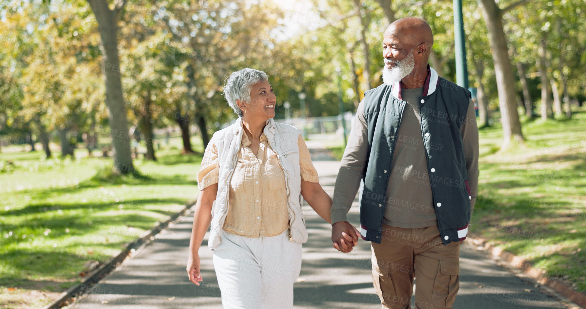 Buy stock photo Mature couple, people and holding hands in park for walk, together and support in New York. Relationship, care and happy with bonding for wellness, relax and smile for retirement as soulmate in love