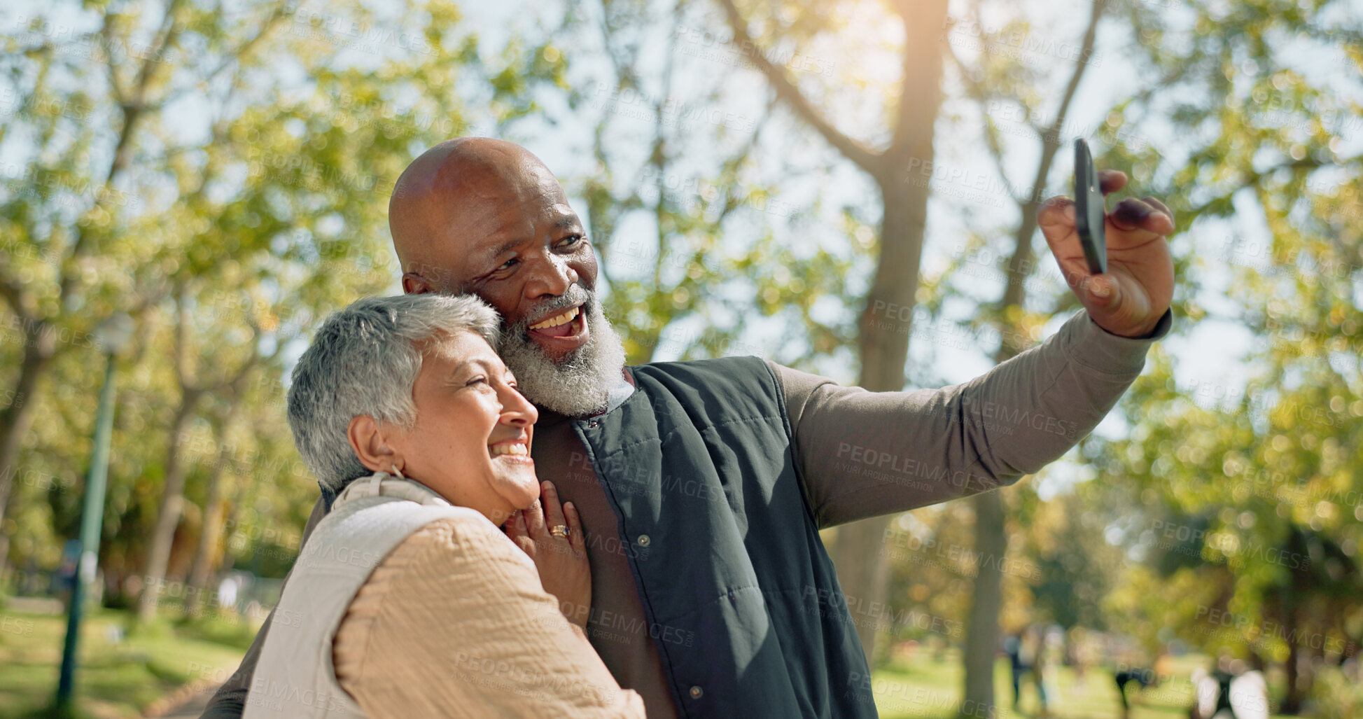 Buy stock photo Senior couple, selfie and love in park with hug or happy of outdoor photography for holiday, travel or vacation. Interracial man and woman in profile picture, memory or bonding in forest for wellness