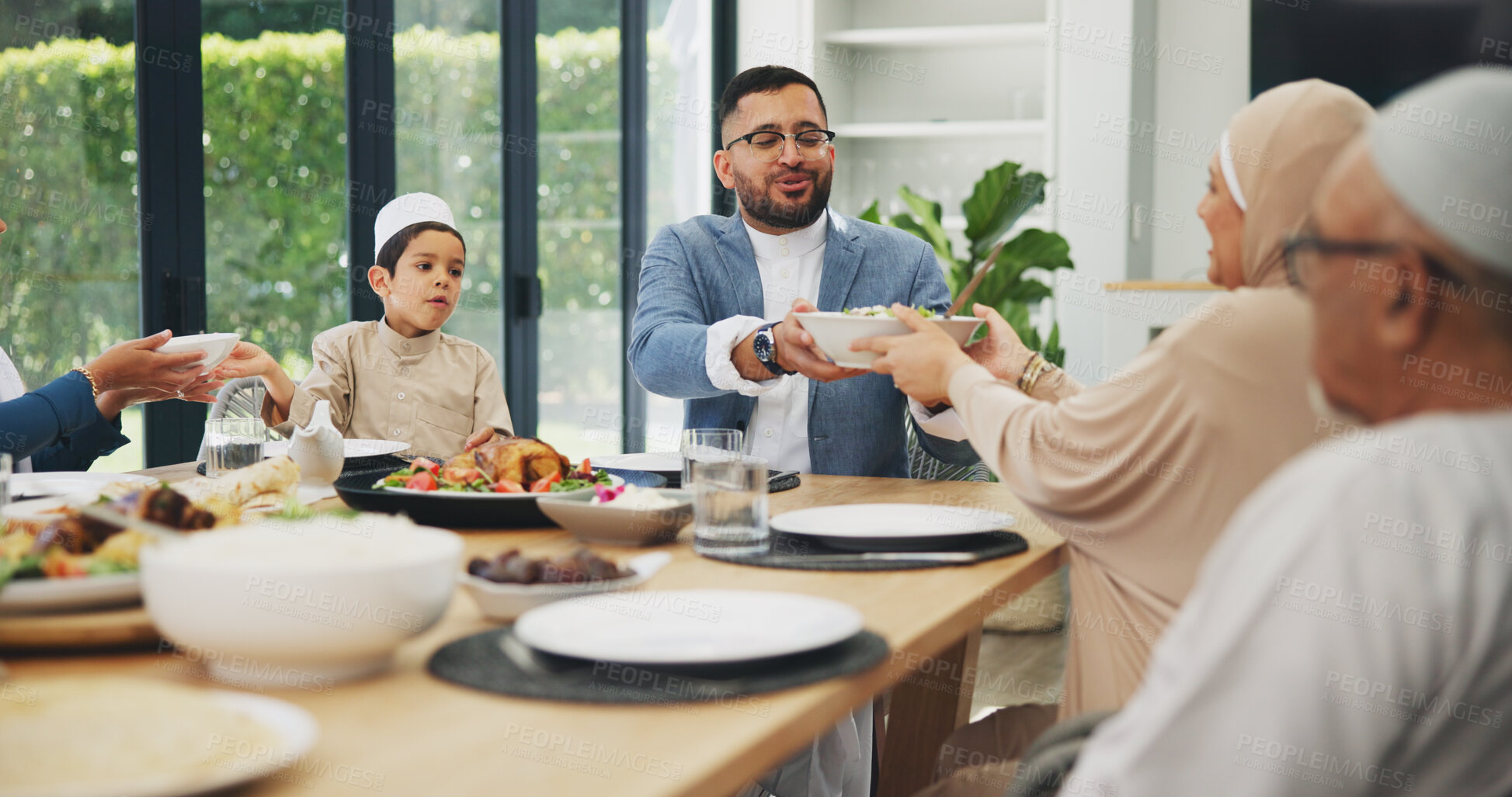 Buy stock photo Muslim, family and dinner in home for eid, islamic celebration and serving food on dining table. Ramadan, culture and religious gathering with conversation, eating and people hosting with lunch