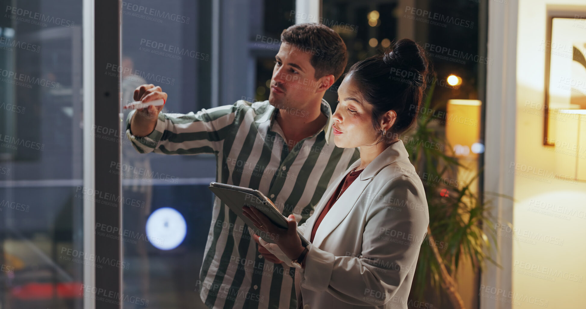 Buy stock photo Night, business people and teamwork with tablet, glass wall and internet with research for proposal, app and stock market. Brainstorming, evening or employees with tech, professional and cooperation