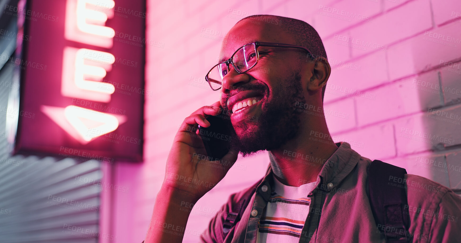 Buy stock photo Happy man, laughing and conversation with phone at night for communication outside bar, pub or neon light. Male person talking with smile in happiness on mobile smartphone for friendly discussion