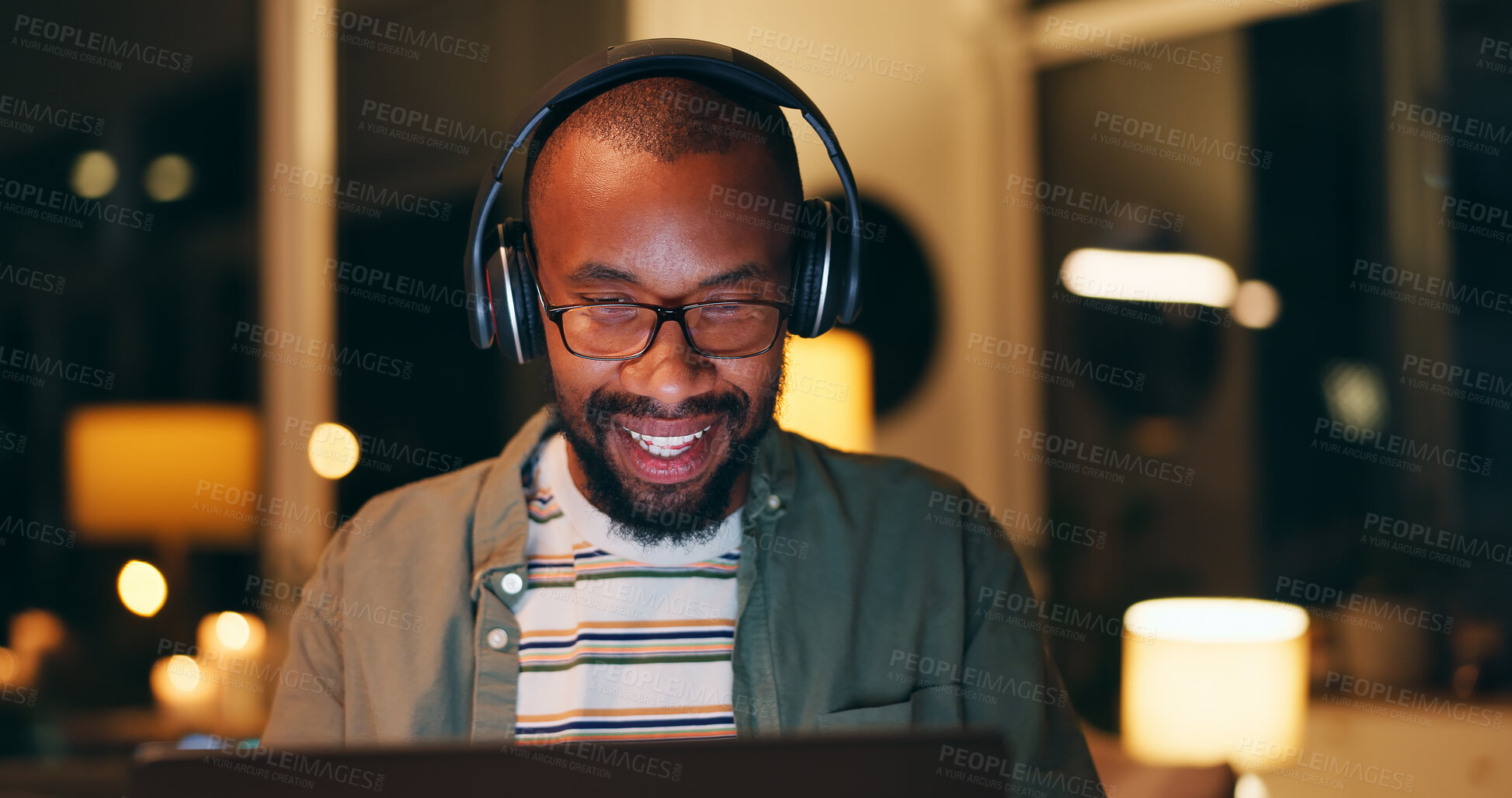 Buy stock photo Night, headphones and black man in office with laptop for listening to music, album or playlist. Smile, creative and employee with computer for project deadline, proposal or feedback at design agency