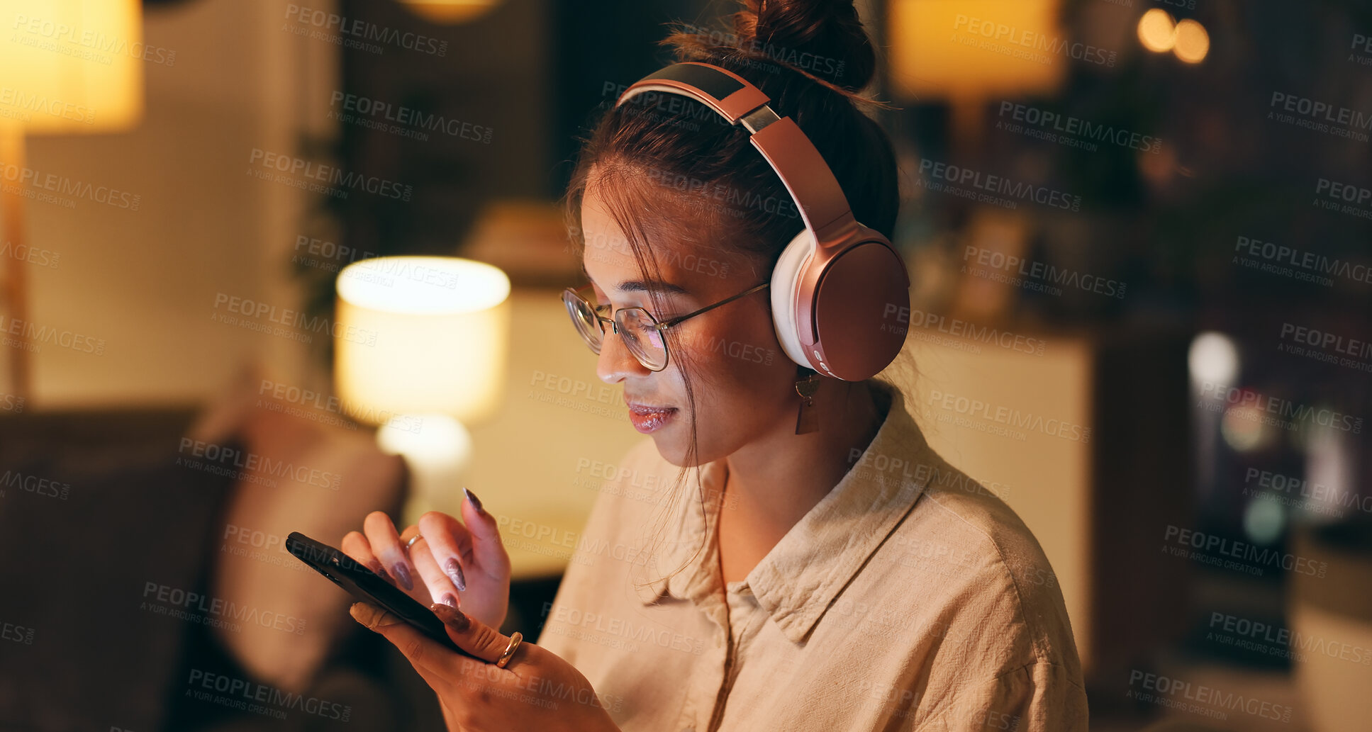 Buy stock photo Smartphone, woman and night for remote work with headphones, choice and searching for music. Female designer, overtime and technology at home for podcast, streaming and entertainment in living room