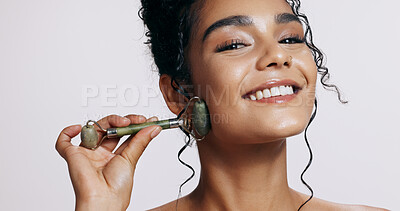 Buy stock photo Face roller, beauty and woman with cosmetics, shine and makeup on grey studio background. Portrait, person and model with tool, wellness and grooming routine with skincare, dermatology and aesthetic