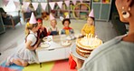 Children, teacher and birthday cake in classroom for school party with friends for celebration, dessert or group. Boys, girls and hats with happiness event at education academy, students or together