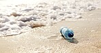 Beach, ocean and plastic bottle in sand for pollution, litter and trash in sea for global warming crisis. Nature, climate change and closeup of garbage in sea to reduce waste, recycling and cleaning