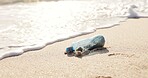 Beach, ocean and plastic bottle in sand for pollution, litter and trash in sea for global warming crisis. Nature, climate change and closeup of garbage in sea to reduce waste, recycling and cleaning