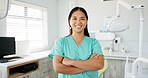 Face, dentist and arms crossed with asian woman in scrubs at hospital for dental care or oral hygiene. Portrait, smile for medical and happy young orthodontist professional at clinic for dentistry