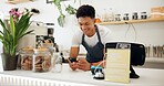 Man, cafe and barista with smile at phone for ecommerce, networking and communication at counter. Male person, small business and waiter with technology for online sale, funny discussion and service