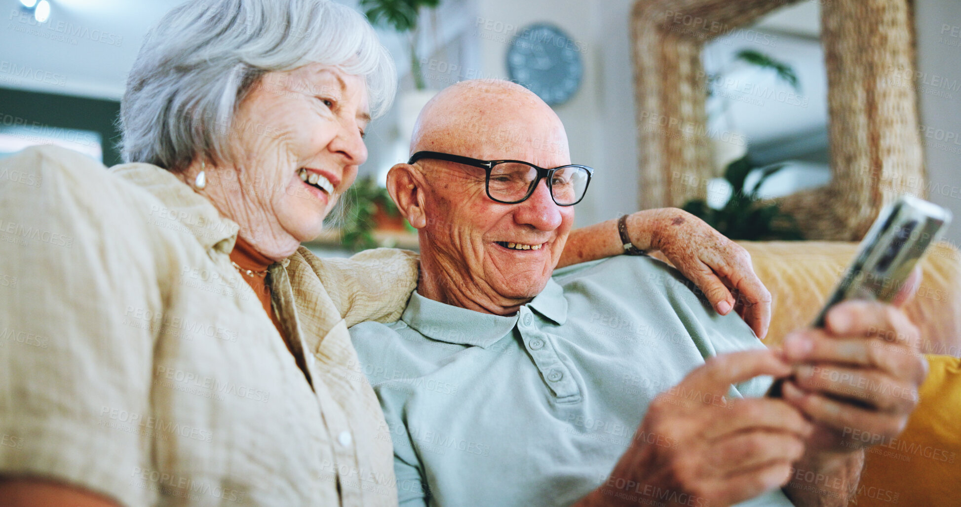 Buy stock photo Senior couple, phone and relax on sofa for hug, choice and help with video, download and streaming in home. Elderly woman, man and smartphone on couch in lounge with thinking for post on social media