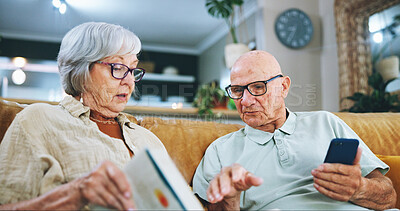 Buy stock photo Senior couple, phone and reading with book on sofa for info, literature game or dictionary at home. Elderly man or woman checking textbook for online word search or crossword in living room at house