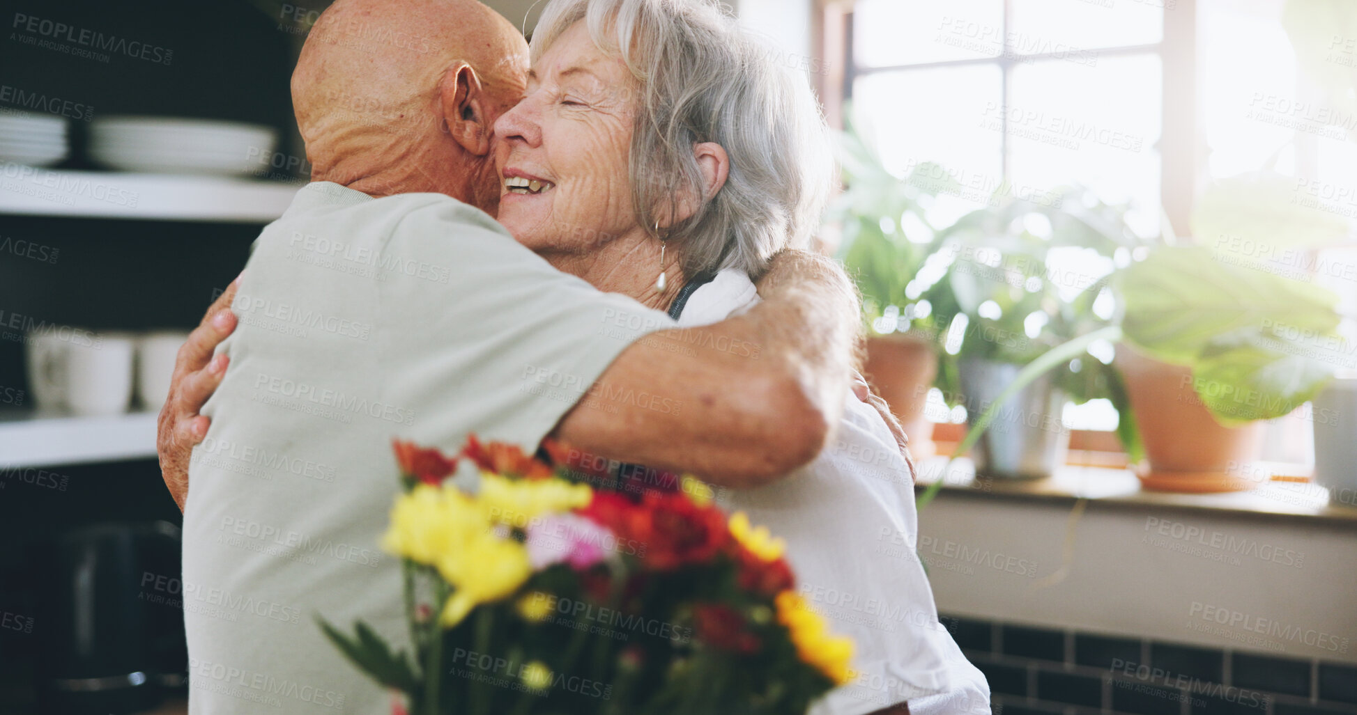 Buy stock photo Senior, couple and hug with flowers in home for anniversary gift, celebration and love in marriage. Elderly, people and happy with embrace or bouquet in kitchen for romance, support or valentines day