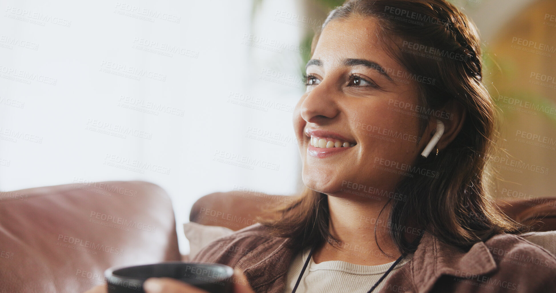 Buy stock photo Woman, smile and earbuds on sofa for music, thinking and audio book or story with coffee in living room. Girl, relaxation and media on couch for entertainment, comedy and listening in lounge with tea