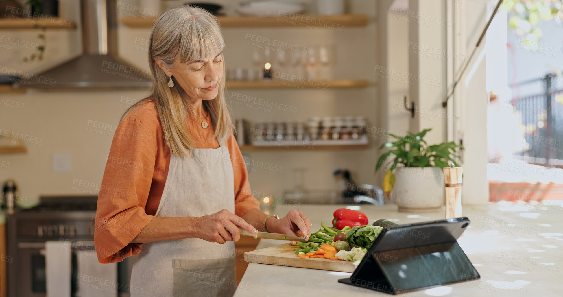 Buy stock photo Home, senior woman and cutting vegetables for dinner, lunch and supper preparation. Kitchen counter, female cook and healthy food with nutrition, vegan meal and tablet for recipe ingredients in house