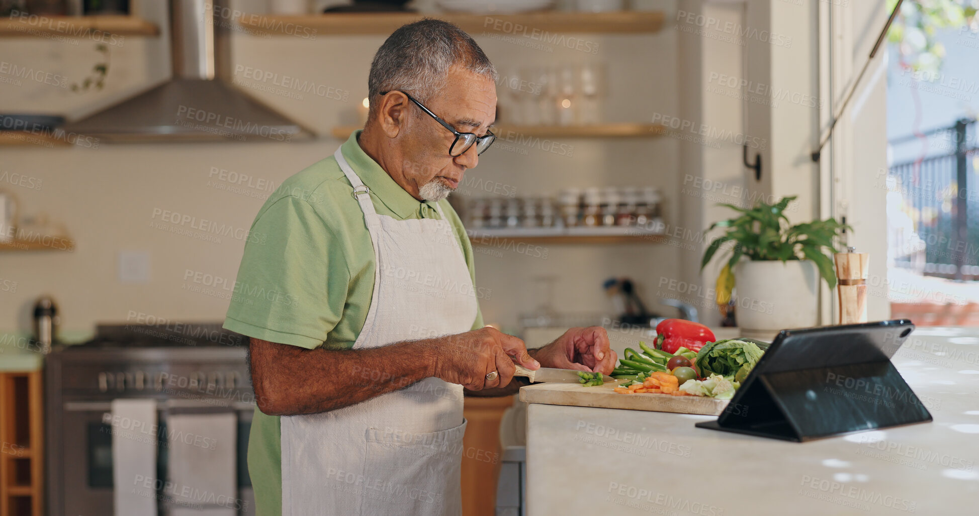 Buy stock photo Home, senior man and cutting vegetables for dinner, lunch and supper preparation. Kitchen counter, male cook and healthy food with nutrition, vegan meal and tablet for recipe ingredients in house