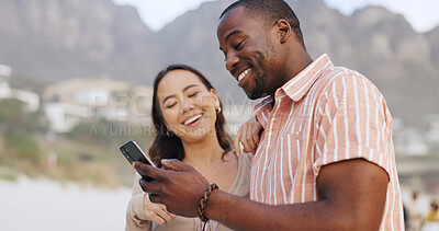 Buy stock photo Interracial couple, beach and phone for social media with happiness, holiday and wellness in USA. Woman, man and together in outdoor for vacation with mobile, reading or search for travel location