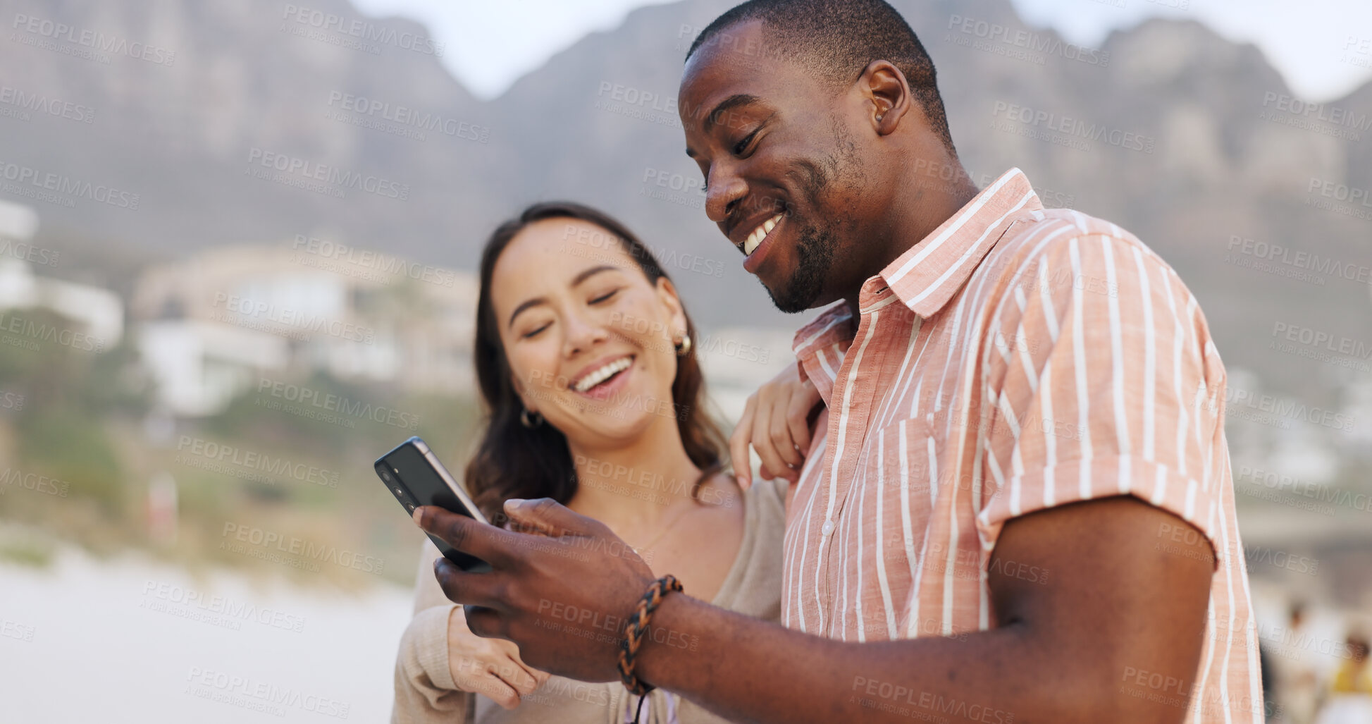 Buy stock photo Interracial couple, beach and phone for social media with happiness, holiday and wellness in USA. Woman, man and together in outdoor for vacation with mobile, reading or search for travel location