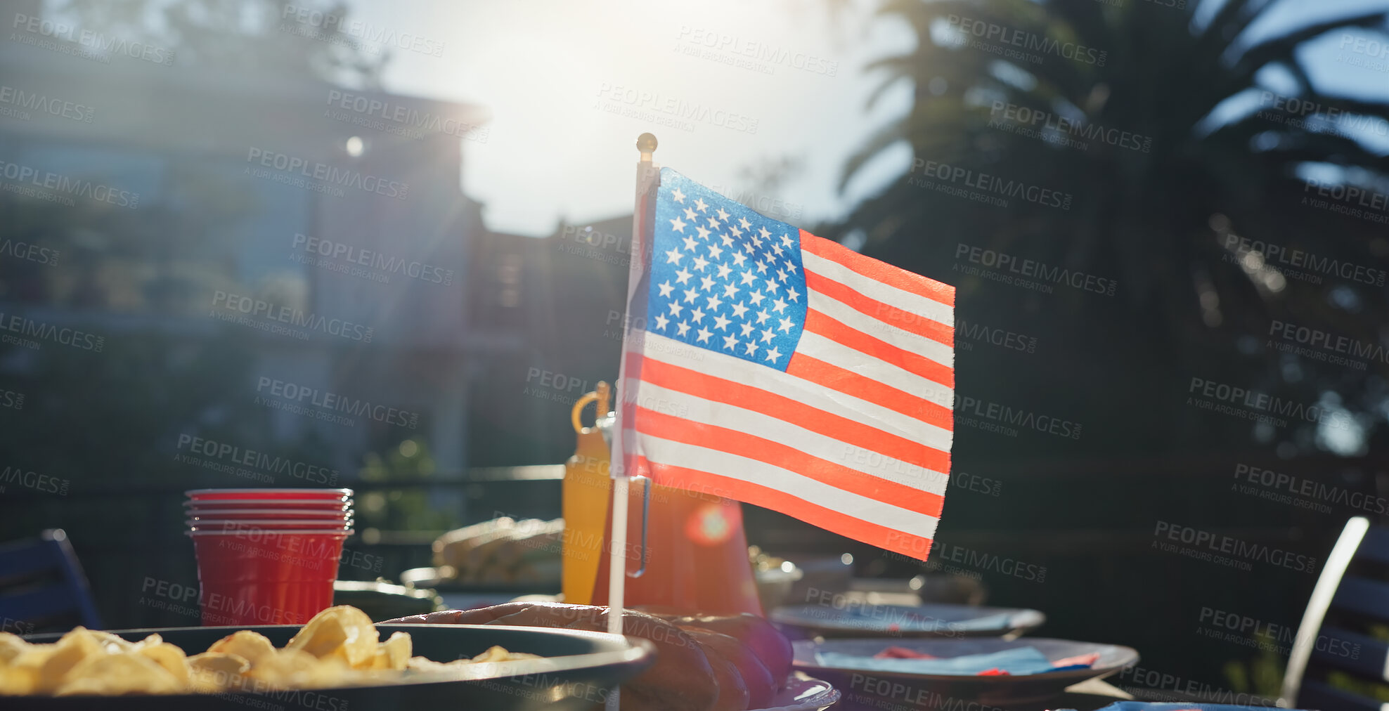 Buy stock photo American flag, party and snacks outdoor for barbecue at reunion lunch for national independence day. Nature, terrace and chips on table for United states holiday event in backyard for country pride.