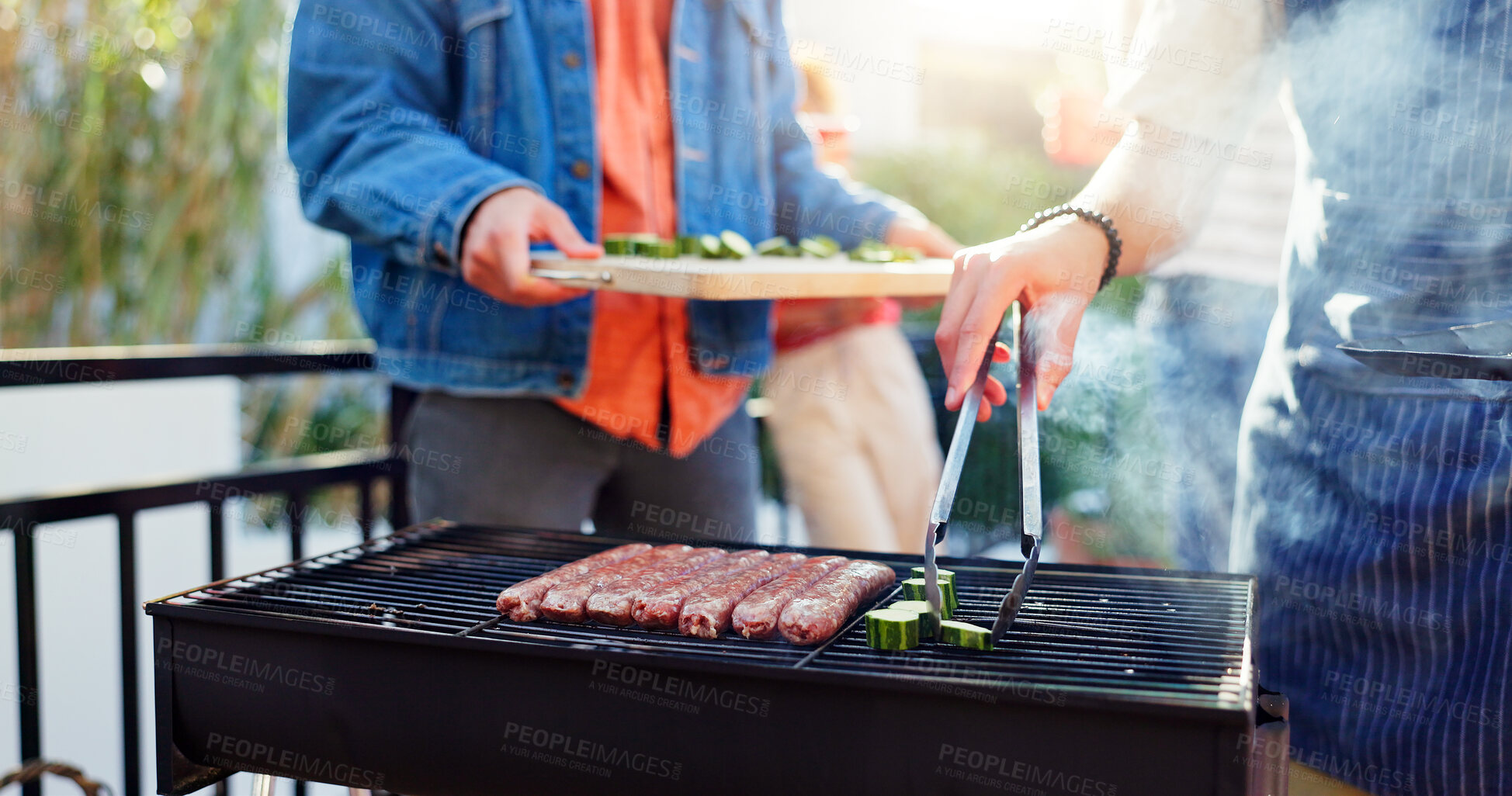 Buy stock photo Barbecue, lunch and friends with sausage outdoor backyard for meal at reunion, social event or party on terrace. Grill, food and men cooking meat and vegetables for bbq dish on weekend at home.