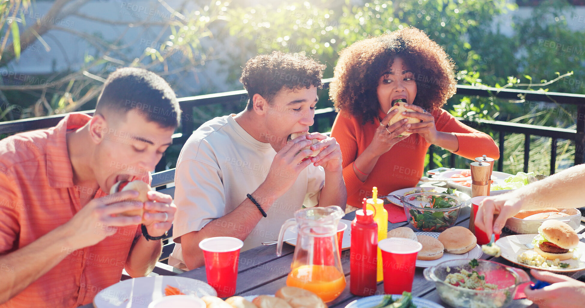 Buy stock photo Friends, group and eating hamburger outdoor on terrace with hunger, reunion and social event in summer. People, barbecue and lunch on patio with food, diversity or celebration with bonding and drinks